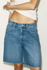 Bermuda de denim azul de tiro medio con cinco bolsillos, trabilla ajustable en la espalda, bajo sin costuras y cierre frontal con botones metálicos.