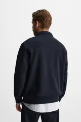 Sudadera negra de cuello alto con cierre frontal de cremallera, corte relaxed fit, manga larga y terminaciones en rib.