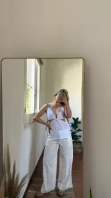 Top blanco de broderie con copas ajustables en la espalda y elástico en la cintura trasera. Breteles ajustables con detalle de ecocuero.