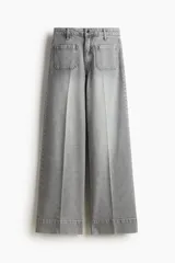 Pantalón de jean de tiro alto, color gris lavado, con pierna ancha y puños doblados. Presenta bolsillos de parche grandes en la parte delantera y bolsillos traseros.