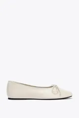 Zapato tipo bailarina color crema, de piel efecto soft, con detalle de lazo en la parte delantera y acabado en punta redonda.