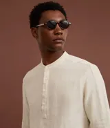 Camisa blanca de manga larga, corte amplio y cuello padre (mandarín). Presenta un frente abotonado con tapeta corta.