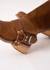 Bota de cuero marrón oscuro con caña media, estribo desmontable y hebilla metálica. Taco de madera de 5cm y suela de caucho.