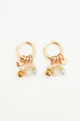 Aros dorados tipo argolla con dijes colgantes de cuentas de vidrio en tonos beige y verde.