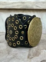 Cinto faja color beige con hebilla circular de metal dorado con diseño labrado.