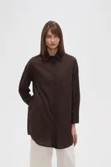 Camisa blanca de algodón con cuello clásico, corte holgado, cierre frontal con botones y mangas largas.