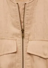 Chaqueta bomber color beige con cierre frontal, cuello redondo, mangas largas con puños elásticos y dos bolsillos delanteros con solapa.