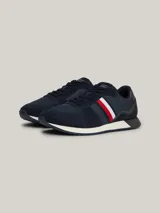 Zapatillas Tommy Hilfiger de estilo running, color azul marino con detalles en rojo, blanco y gris. Confeccionadas en poliéster con interior de poliéster, plantilla extraíble de goma termoplástica y poliuretano, y suela de goma dentada. Presentan cinta distintiva en el lateral, paneles con mezcla de texturas y parche con logo en la lengüeta.