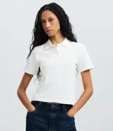 Blusa polo de algodón color blanco, con cuello clásico, mangas cortas y cierre frontal de tres botones.