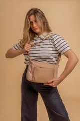 Bandolera de diseño moderno, color beige rosado, con correa regulable y bolsillo frontal con cierre.