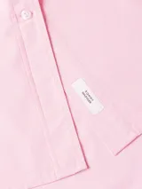 Vestido camisero Tommy Hilfiger color rosa, de corte oversize y largo hasta la rodilla. Confeccionado en algodón orgánico, con cuello inglés, cierre de botones, puños con botón y logo bordado en el puño.