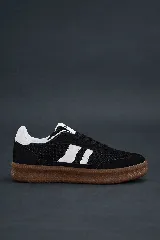 Championes urbanos de caña baja, color negro, con tres franjas laterales en blanco y suela de goma color caramelo. Presentan puntera reforzada y talón en material blanco.