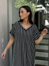 Vestido largo tejido a rayas verticales blancas y negras, con escote en V y tajos laterales.