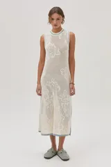 Vestido midi tejido de punto color crudo, con calados florales, calce recto, tajos laterales y detalles en celeste en cuello, sisas y ruedo.