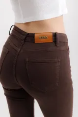 Pantalón jean marrón acampanado con detalle desflecado en el bajo y tiro medio.