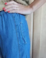 Pantalón de corte amplio en denim oscuro, con detalles de costura y cintura ajustable.