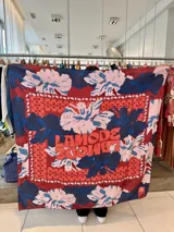 Pañuelo cuadrado de gran tamaño con estampado floral en tonos rojo, azul y rosa. Incluye el logo de la marca en el centro.