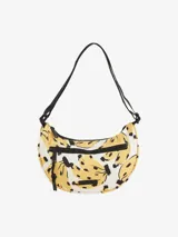 Bolso tipo bandolera con estampado de bananas amarillas y negras sobre fondo blanco. Tiene correa negra ajustable y cierre superior con cremallera.