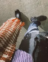 Bota corta de cuero color marrón, con taco de madera y punta cuadrada. Presenta una correa con hebilla alrededor del tobillo.