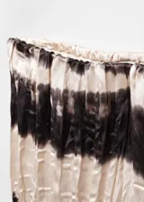 Pantalón plisado con estampado tie-dye en tonos beige y negro, diseño largo y cintura elástica.