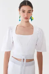 Top de tejido liviano con escote recto y mangas tipo globo de poplín 100% algodón, con tiras para ajustar en la cintura.