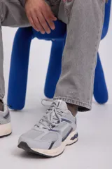 Zapatillas deportivas grises con detalles en azul marino. Confeccionadas en tejido de malla con forro de poliéster y suela de goma.