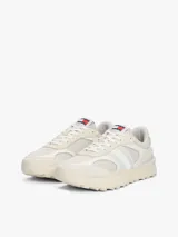 Zapatillas Tommy Jeans de estilo running, color blanco hueso, con exterior de ante, interior de poliéster y suela gruesa de goma con tacos. Presentan paneles con mezcla de texturas y detalles distintivos de la marca.