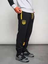 Pantalón de jogging negro con cordones amarillos, puños ajustados y escudo del Club Atlético Peñarol bordado en amarillo.