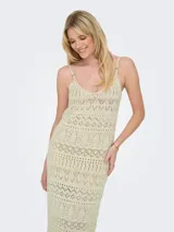 Vestido largo tejido color crudo, con escote en V, breteles finos y diseño calado.