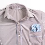 Pijama celeste de terciopelo, compuesto por una camisa de manga larga con botones y vivo blanco, bolsillo en el pecho y un pantalón recto con elástico en la cintura.