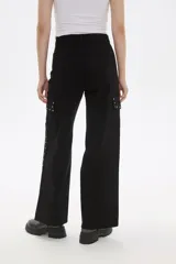 Pantalón de algodón color blanco, de corte ancho y tiro alto, con bolsillos laterales y detalle de tachas metálicas en los laterales.