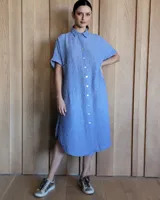 Vestido camisero de lino color celeste con botones blancos, corte recto y mangas cortas.
