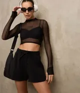 Blusa deportiva de tule negro, con cuello alto, mangas largas y estampa frontal con la palabra 'muse'.