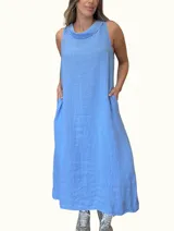 Vestido largo sin mangas color azul claro, confeccionado en lino, con cuello tipo buche o drapeado. Presenta un calce holgado y bolsillos laterales.