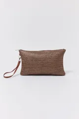 Sobre tipo clutch color marrón tejido en rafia, con cierre superior y tira de cuero sintético marrón en el lateral.