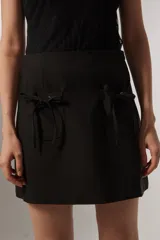 Falda negra ajustada al cuerpo, con bolsillos frontales y detalles de cordón.