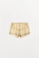 Shorts color crema de tiro alto con cintura elástica, bordados florales y puntilla a tono.
