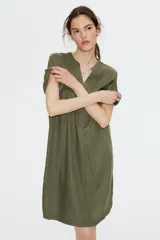 Vestido túnica a la rodilla en tejido liviano de viscosa color verde oliva con cuello mao y abertura en V. Modelo de corte holgado con hombros levemente caídos, mangas cortas y bajo recto con tajos laterales.