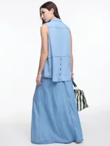 Camisa sin mangas en denim color celeste, confeccionada en 100% lyocell. De corte recto y largo medio, presenta cartera escondida en el frente y un bolsillo plaqué en el pecho. En la espalda, tiene botones decorativos alineados en abertura vertical y pespuntes a contratono.