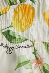 Blusa corta con escote en V pronunciado, elásticos finos en la cintura y peplum. Mangas globo cortas con elástico oculto en los puños. Estampado de limones y hojas verdes.
