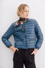 Campera azul de nylon rellena con pluma, corte holgado y largo a la cintura. Tiene bolsillos con cierre y detalle de vivos.