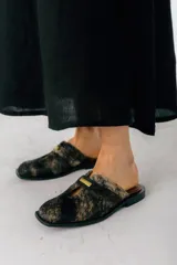 Zuecos negros de cuero con detalle metálico plateado en la tira superior.