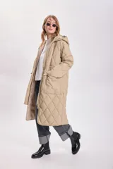 Campera color beige con capucha, cierre frontal con cremallera y broches a presión, bolsillos laterales y diseño acolchado con patrón de rombos.