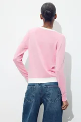 Chaqueta celeste de punto con cuello redondo y manga larga. Tiene cierre frontal con botones y detalle de falsos bolsillos delanteros con ribete blanco.