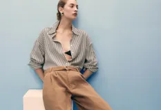 Short de algodón color marrón, con tiro medio, diseño recto, pinzas delanteras y cinturón ajustable. Presenta bolsillos laterales y dos bolsillos de ribete en la parte posterior.