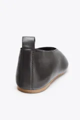 Zapato tipo bailarina de piel color negro, con puntera redondeada y detalle de tira trasera.