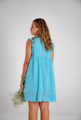 Vestido corto blanco de algodón con bordado tipo broderie anglaise, escote en V y mangas cortas con volado. Presenta un corte imperio con frunce bajo el busto.