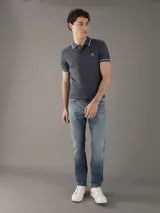 Chomba Calvin Klein color gris con cuello polo, tapeta de dos botones, logo bordado en el pecho y ribetes blancos en cuello y mangas. Corte slim fit.