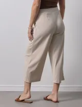 Pantalón capri plisado color beige, marca Dictionary, con pretina ancha elastizada y bolsillos delanteros.