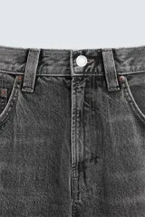 Pantalón de jean gris oscuro, corte amplio, con cinco bolsillos, efecto lavado y cierre frontal con cremallera y botón.